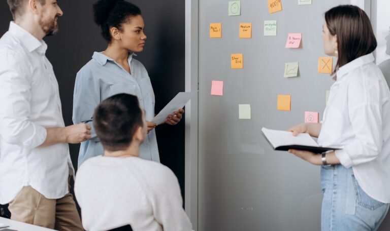 Diverse team collaborating in an office, discussing ideas using sticky notes and notepads.